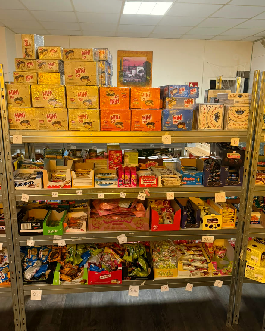 Regal mit Kartons voller Waffeln und Schokokuchen, darunter Süßigkeiten mit Preisschildern
